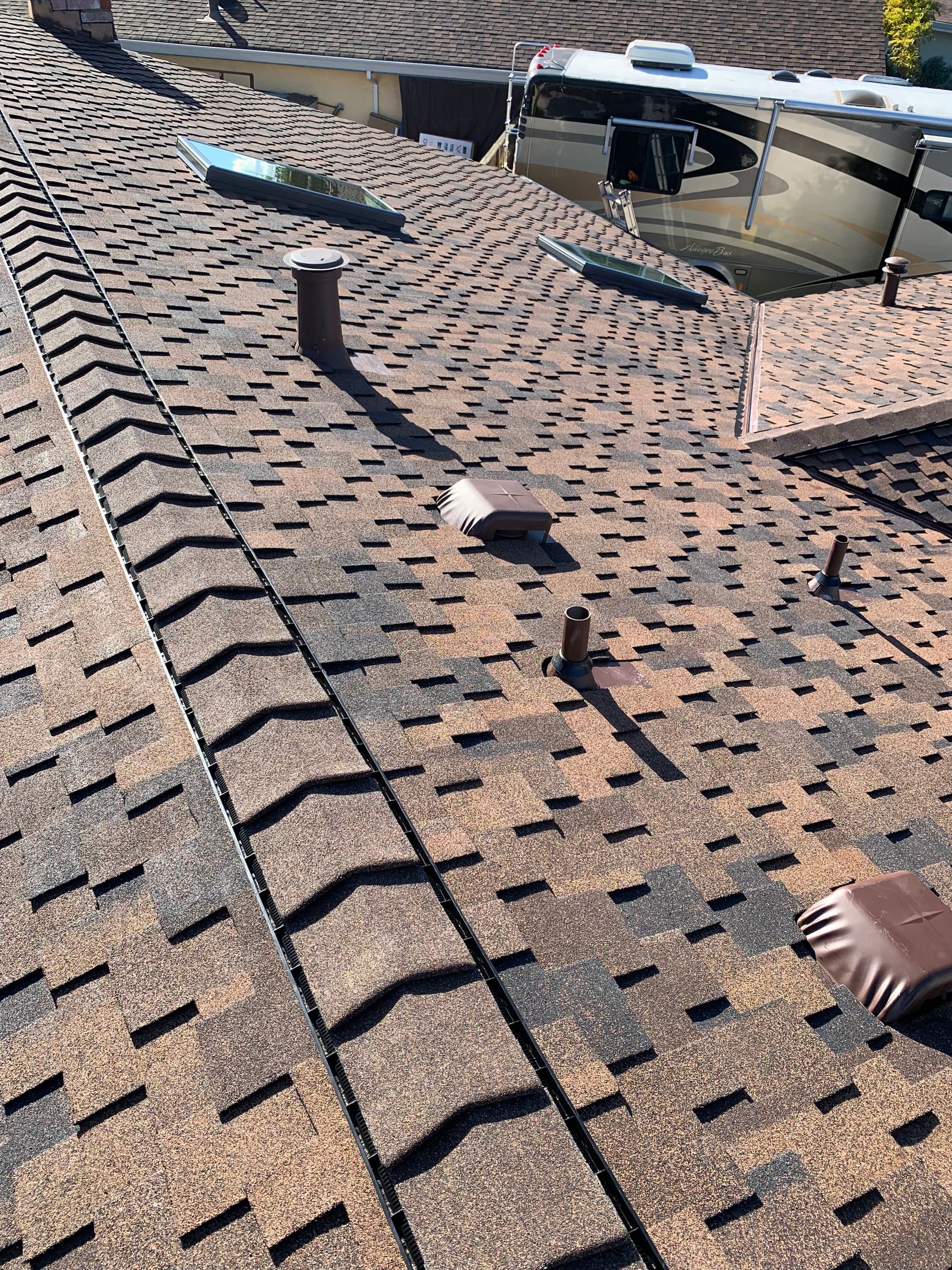 Close-up of finished shingle roof detail with vent boots and ridge line